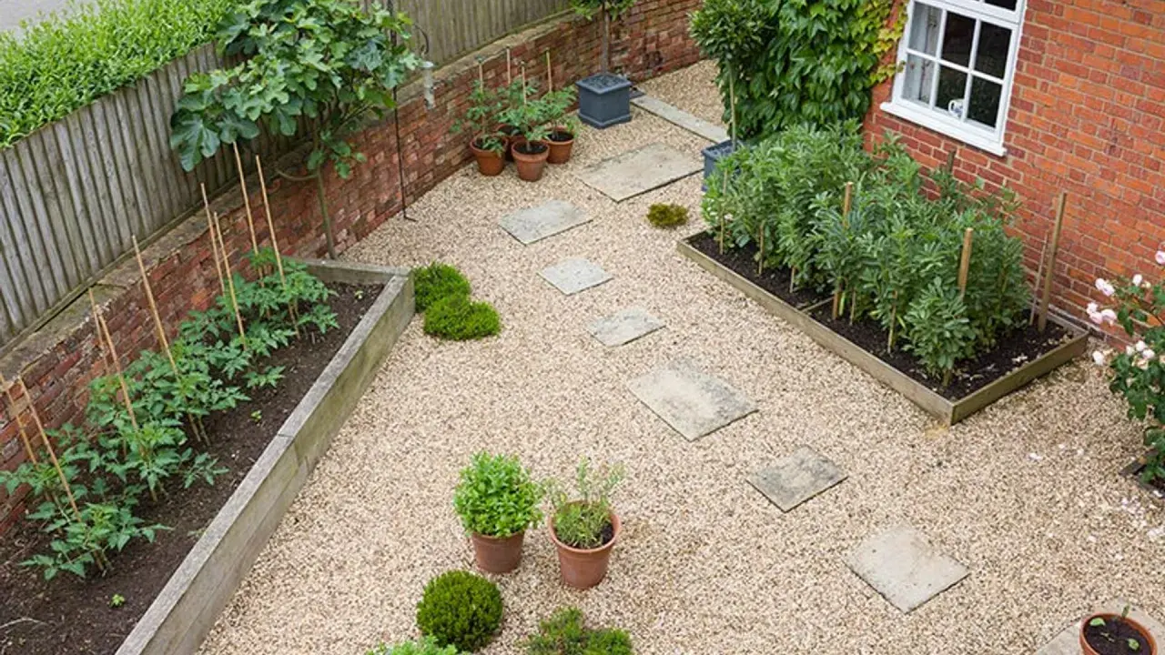 Un huerto urbano en terraza con tomates y habas en bancales de madera, senderos de grava y plantas en macetas.