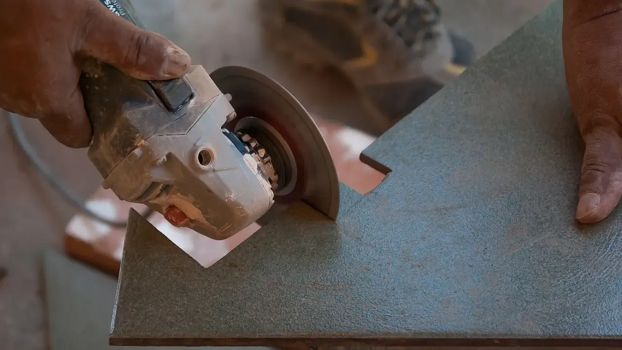 Mano sujetando una radial para cortar azulejos con precisión.