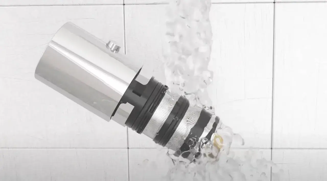 Detalle de un grifo termostático bajo un chorro de agua, mostrando su diseño y cómo limpiarlo.