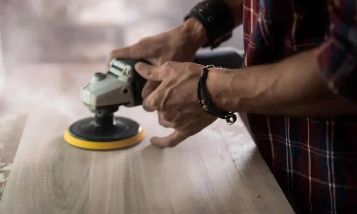 Man lijando madera con una lijadora, mostrando la diferencia entre lijadora orbital y excéntrica.