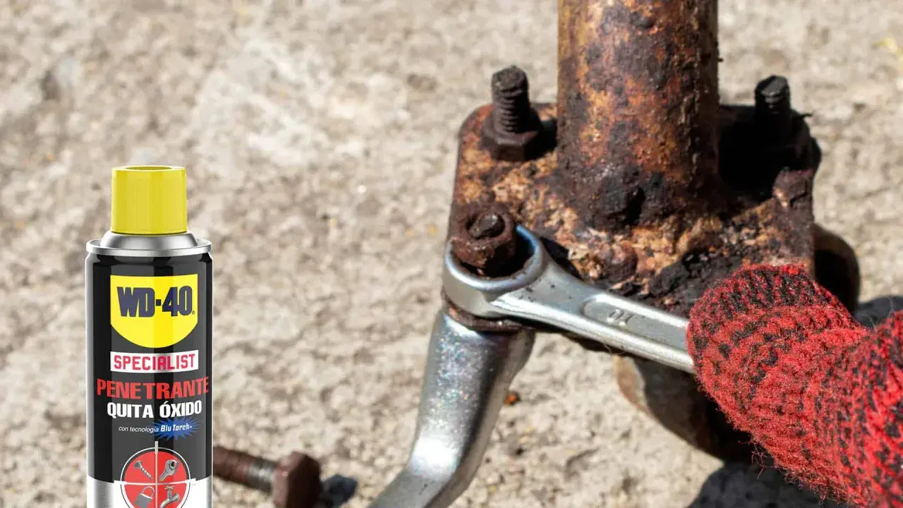 WD-40 ayuda a sacar tornillo roto de pieza oxidada. Llave inglesa y guante rojo en acción.