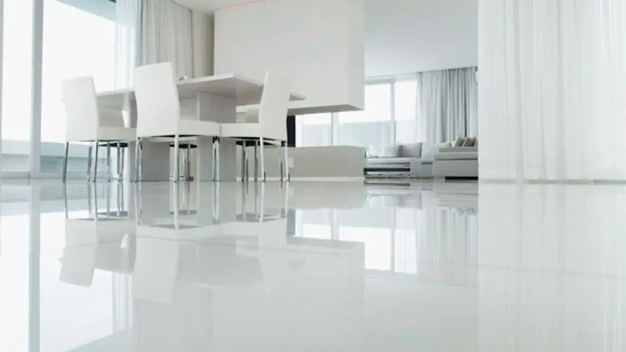 Un moderno salón con un impecable suelo resina epoxi vivienda, reflejando la luz y el mobiliario minimalista.