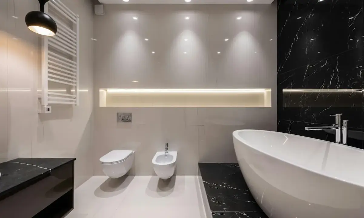 Radiador toallero blanco colgado en pared junto a un inodoro y bidet, ideal para baños modernos.