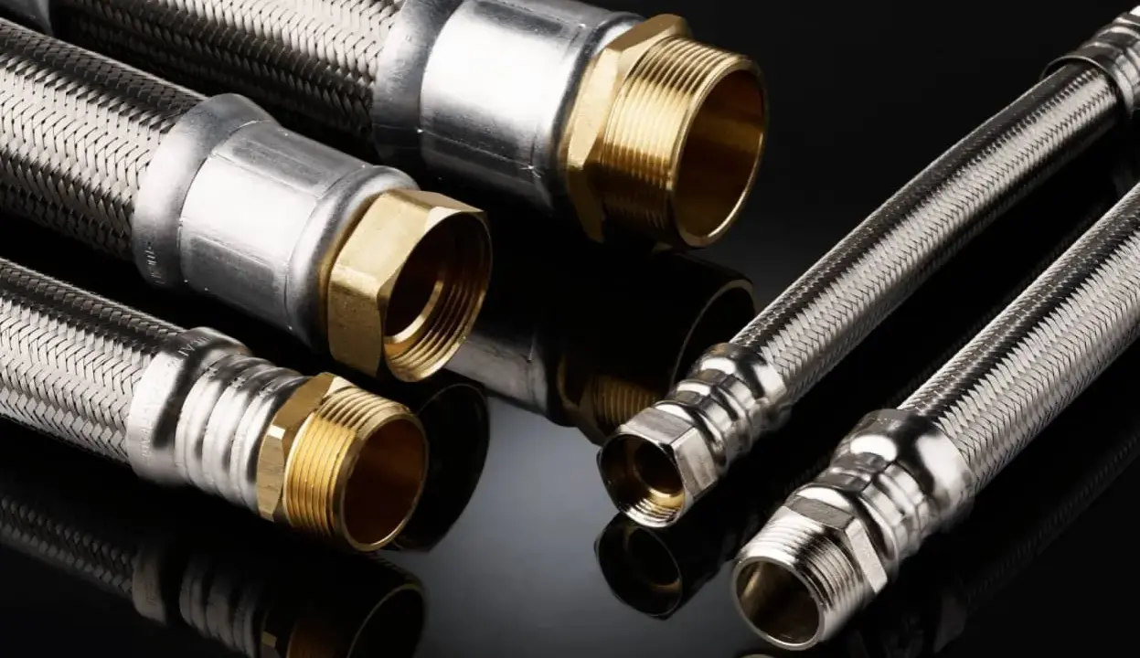 Detalles de una instalación de tubería PEX con mangueras flexibles de acero inoxidable y conexiones de latón.