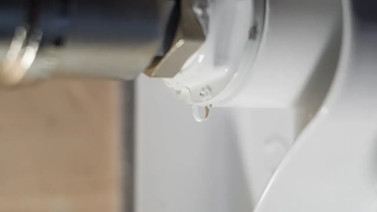 Una gota de agua cae de la rosca de un radiador. El radiador pierde agua por la rosca, indicando una posible fuga.