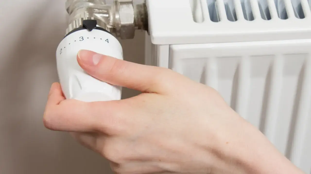 Mano ajustando el termostato para abrir radiador derecha o izquierda.