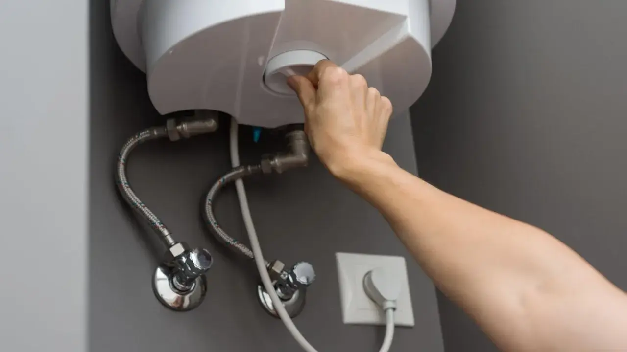 Mano girando el dial para cerrar la llave de paso del termo eléctrico.