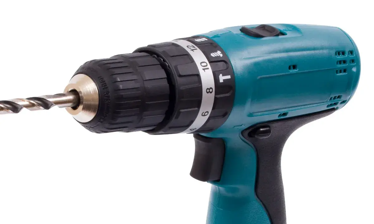 Taladro percutor inalámbrico de color turquesa con broca metálica. El simbolo taladro percutor se ve en su selector de torque.
