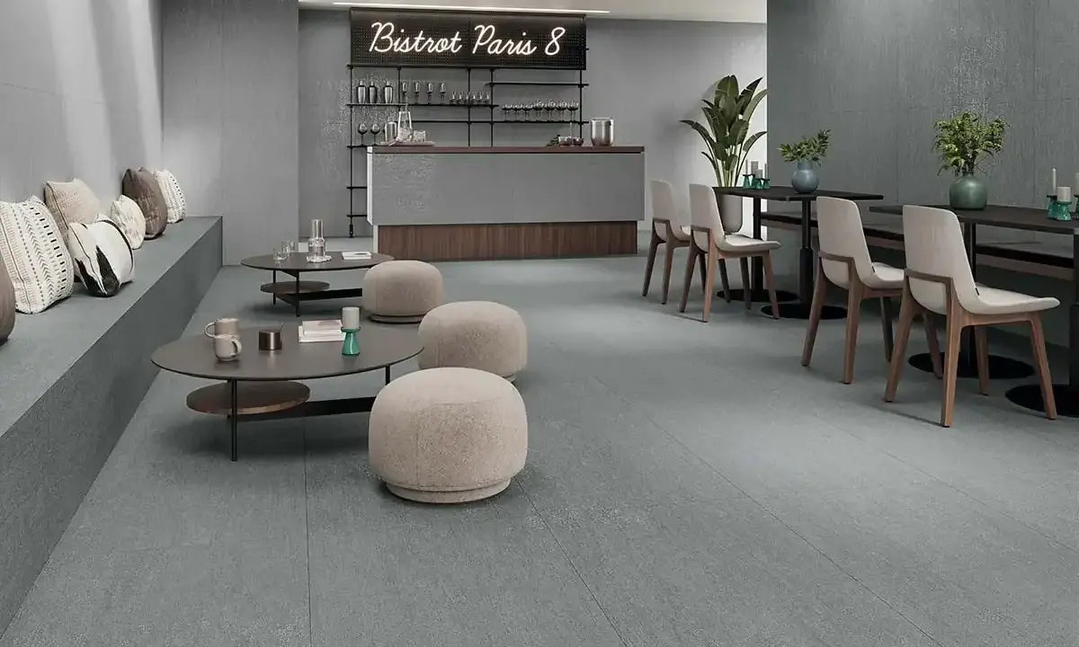 Modern café con suelo de baldosas grises, asientos de banco, mesas bajas y sillas. Ideal para aprender como colocar baldosas en el suelo.
