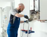 Técnico revisa el cableado interno de una caldera, mostrando cómo funciona.