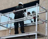 Trabajador en andamio modular, uno de los tipos de andamios, limpiando una ventana.
