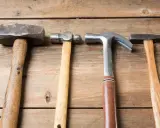 Cuatro martillos de diferentes clases: uno de orejas, uno de bola, uno de carpintero y uno de ebanista, sobre una superficie de madera.