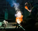 Soldador usa un electrodo rutilo para crear uniones fuertes. El humo y las chispas iluminan la escena industrial.