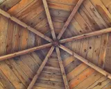 Estructura radial de vigas de madera que se unen en el centro, formando unos techos de madera rústicos y acogedores.