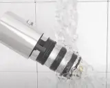 Detalle de un grifo termostático bajo un chorro de agua, mostrando su diseño y cómo limpiarlo.