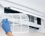 Mano con guante azul extrae filtro de aire acondicionado. Aquí es donde están los filtros del aire acondicionado por conductos.