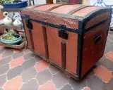 Un baúl antiguo restaurado, con detalles metálicos y acabado en cobre texturizado, listo para guardar tesoros.