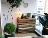 Mueble de madera para camuflar aire acondicionado exterior, decorado con plantas y objetos.