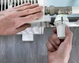 Mano ajusta el termostato de un radiador. El radiador solo calienta la mitad derecha, indicando un posible problema.