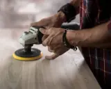 Man lijando madera con una lijadora, mostrando la diferencia entre lijadora orbital y excéntrica.