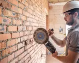 Obrero con casco y gafas protectoras listo para cortar pared con radial.