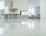 Un moderno salón con un impecable suelo resina epoxi vivienda, reflejando la luz y el mobiliario minimalista.