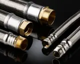 Detalles de una instalación de tubería PEX con mangueras flexibles de acero inoxidable y conexiones de latón.