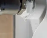 Una gota de agua cae de la rosca de un radiador. El radiador pierde agua por la rosca, indicando una posible fuga.