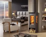 Estufa moderna de leña, un ejemplo de los diversos tipos de estufas, calienta un dormitorio acogedor con vistas al atardecer.