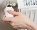 Mano ajustando el termostato para abrir radiador derecha o izquierda.