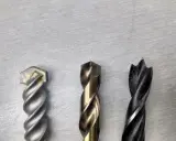 Tres brocas diferentes: una para mampostería, una para metal y una para madera. Cada broca tiene un diseño único para su propósito.