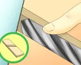 Proceso de afilado de brocas con una piedra de afilar. Se muestra una mano sujetando la broca contra la piedra.