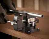 Manos enguantadas ajustan un tubo metálico en un tornillo de banco Stanley Fatmax, herramienta esencial para fijar piezas.