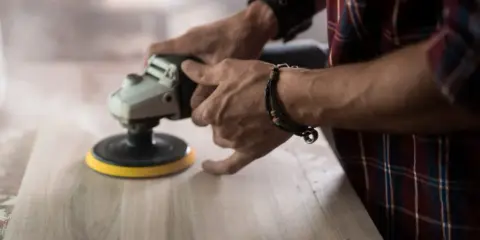 Man lijando madera con una lijadora, mostrando la diferencia entre lijadora orbital y excéntrica.
