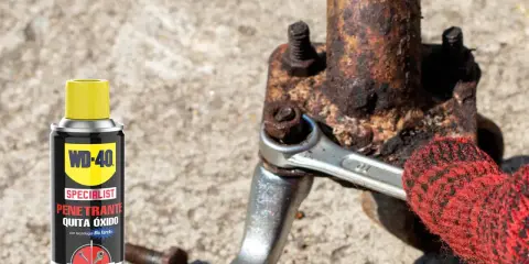 WD-40 ayuda a sacar tornillo roto de pieza oxidada. Llave inglesa y guante rojo en acción.
