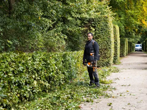 Hombre podando setos, mostrando diferentes tipos de setos a lo largo de un camino.