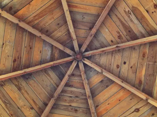 Estructura radial de vigas de madera que se unen en el centro, formando unos techos de madera rústicos y acogedores.