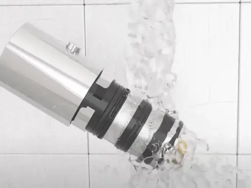 Detalle de un grifo termostático bajo un chorro de agua, mostrando su diseño y cómo limpiarlo.