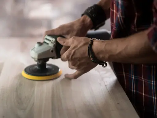 Man lijando madera con una lijadora, mostrando la diferencia entre lijadora orbital y excéntrica.