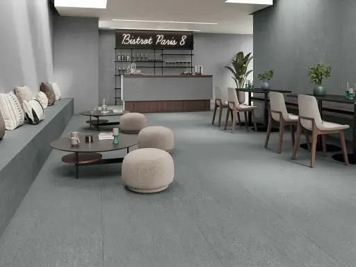 Modern café con suelo de baldosas grises, asientos de banco, mesas bajas y sillas. Ideal para aprender como colocar baldosas en el suelo.