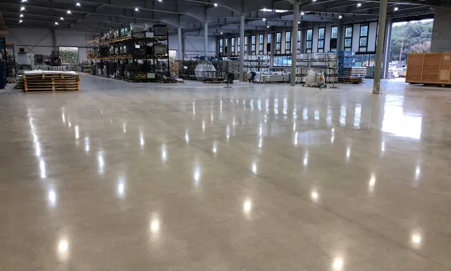 Almacén con suelo de hormigón pulido, ideal para el tratamiento de litio. Estanterías metálicas y palets de madera.