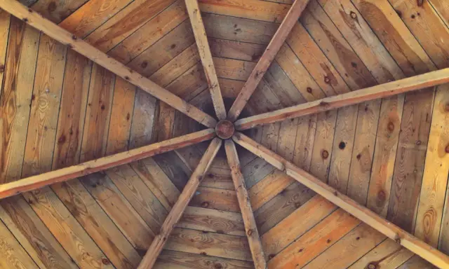Estructura radial de vigas de madera que se unen en el centro, formando unos techos de madera rústicos y acogedores.