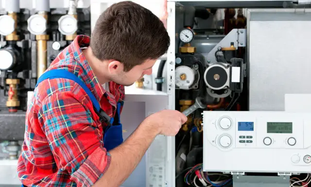 Técnico revisa una caldera de gas con problemas, usando una llave inglesa para reparar el sistema.