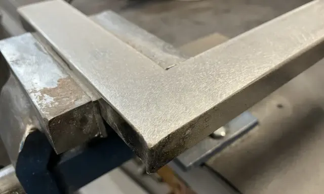 Un ángulo metálico en una escuadra de carpintero, listo para ser pulido con herramientas de acabado.