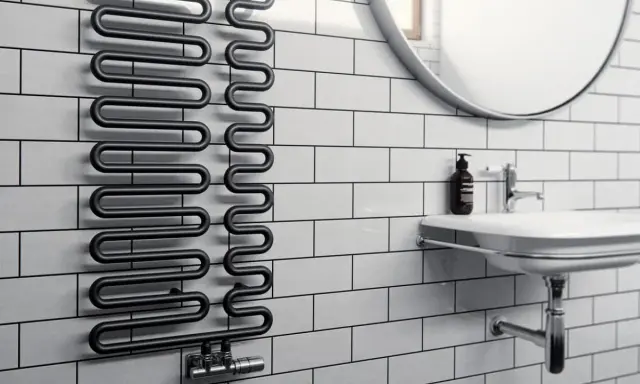 Radiador toallero negro con diseño ondulado, ideal para secar toallas o calentar el baño. Un radiador normal con estilo.