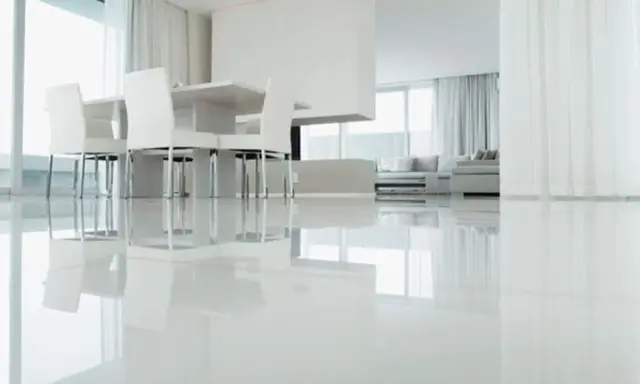 Un moderno salón con un impecable suelo resina epoxi vivienda, reflejando la luz y el mobiliario minimalista.