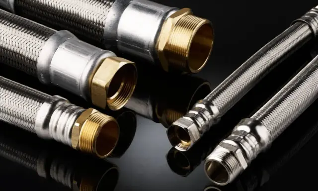 Detalles de una instalación de tubería PEX con mangueras flexibles de acero inoxidable y conexiones de latón.