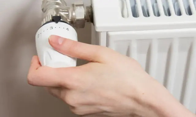 Mano ajustando el termostato para abrir radiador derecha o izquierda.