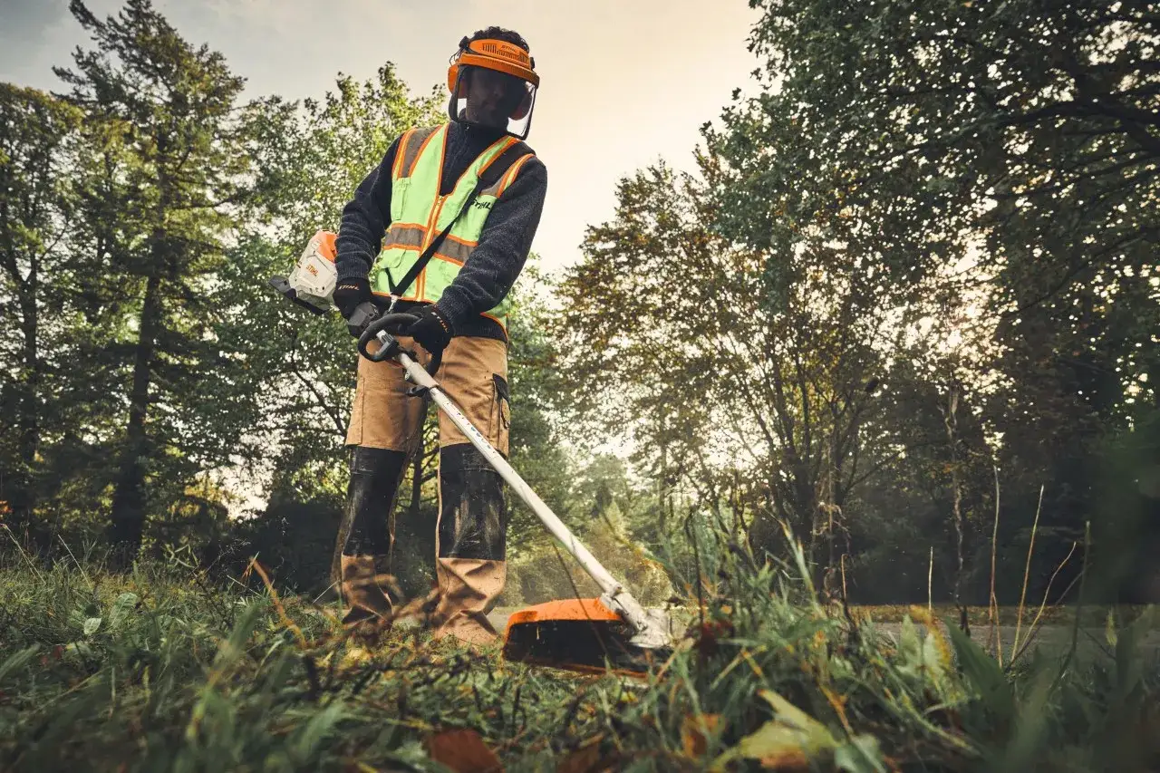 Hombre con equipo de protecci&oacute;n usando desbrozadora, una herramienta de la segunda marca de Stihl, en un entorno natural.