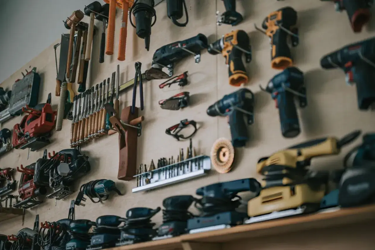 Un taller organizado con herramientas para trabajar la madera: taladros, lijadoras, sierras, cinceles y martillos colgados en la pared.